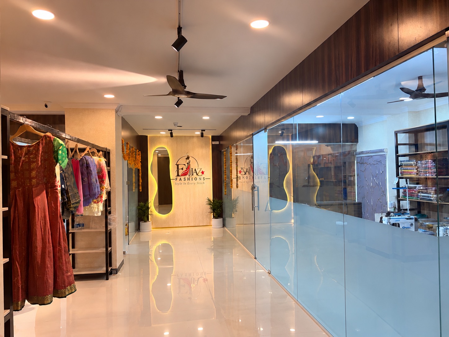 The boutique interior with clothing rails, an illuminated mirror, and a glass partition