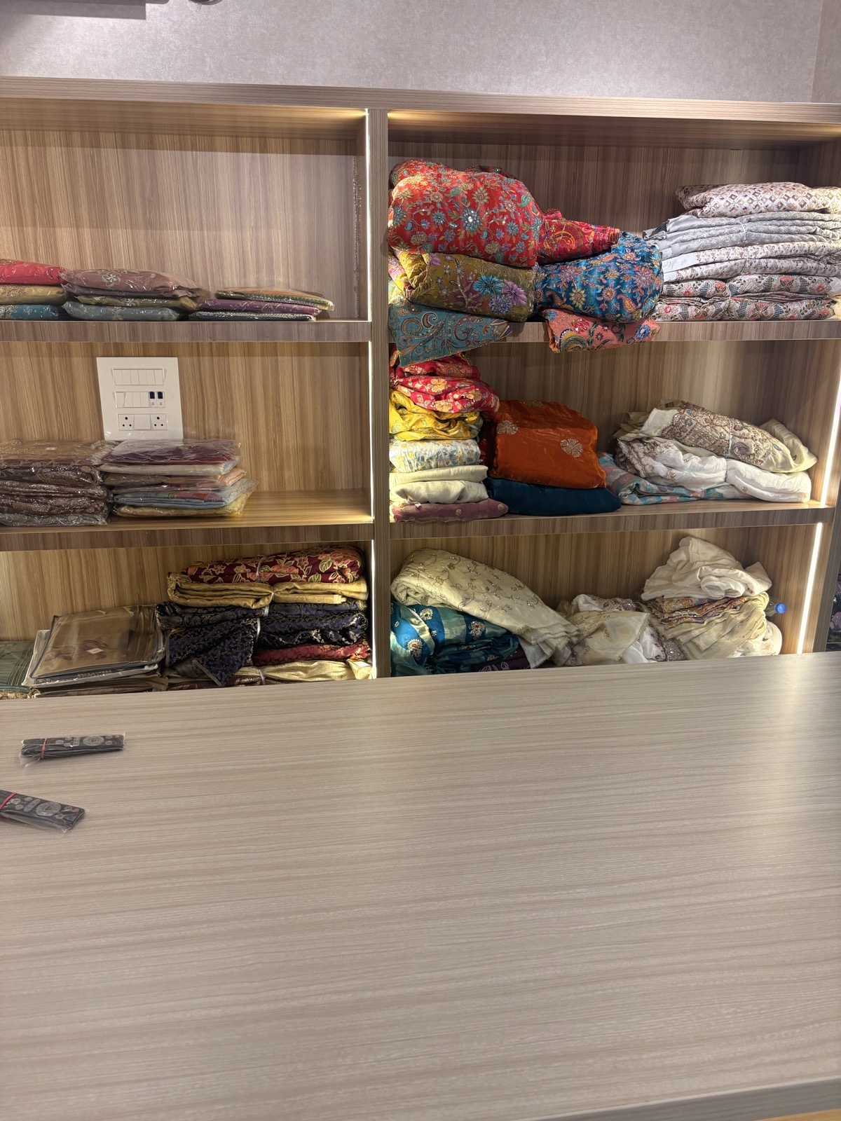 Colourful folded fabrics on the wooden shelves at Ejaz Fashion